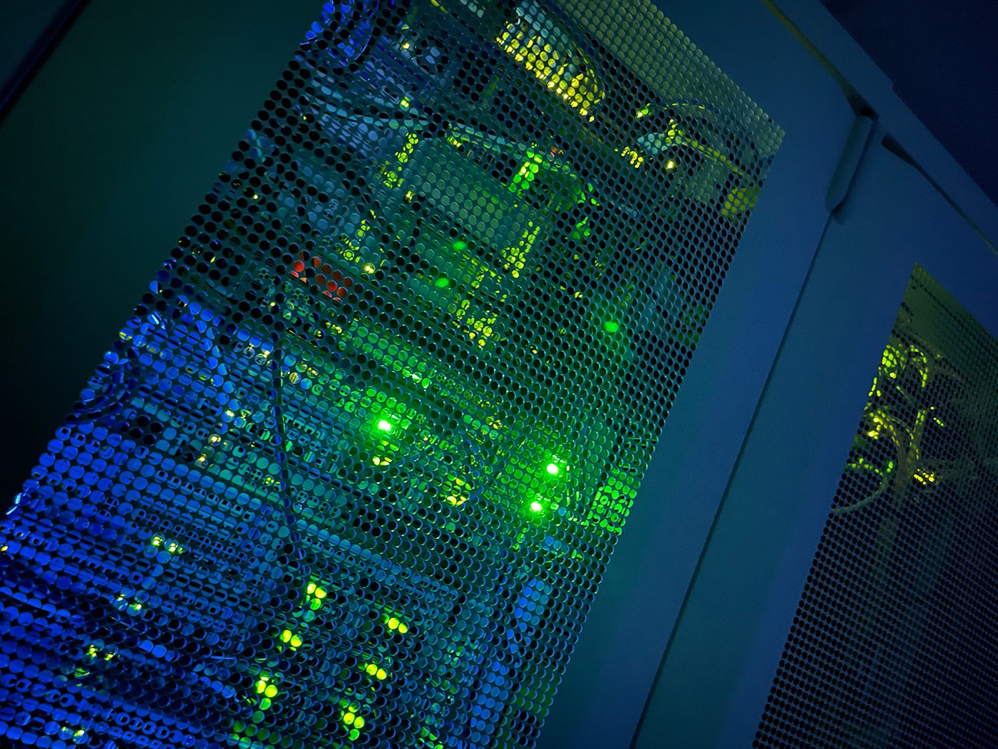 Close-up of a colocation cabinet door with server status lights behind the mesh